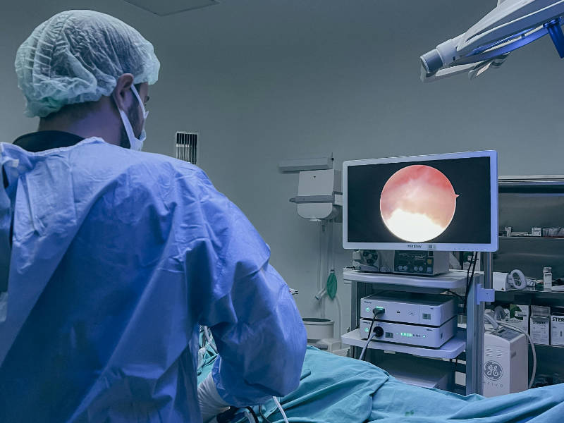 Doctor using an endoscope medical imaging device on a patient in a surgery room.